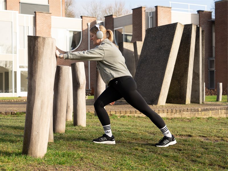 Hardloper rekt de kuit tijdens een warming-up buiten
